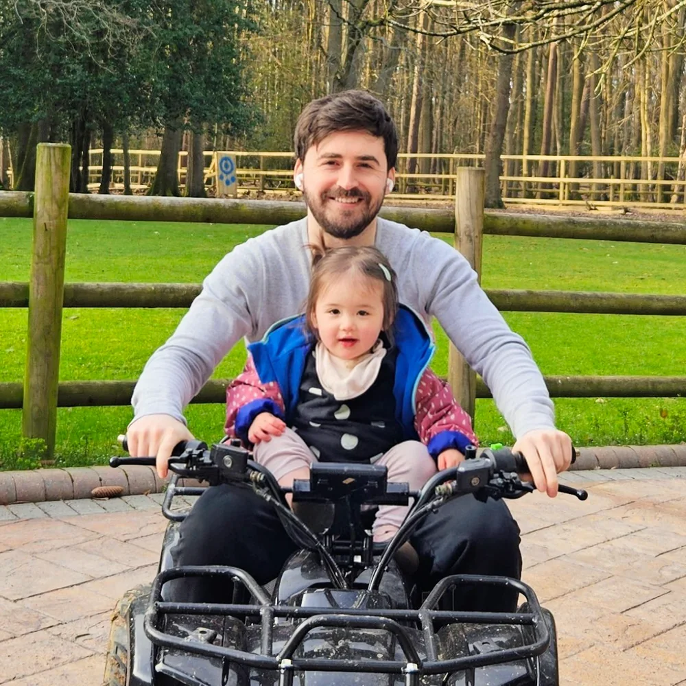 Alex Hawke smiling on a quad bike with his daughter
